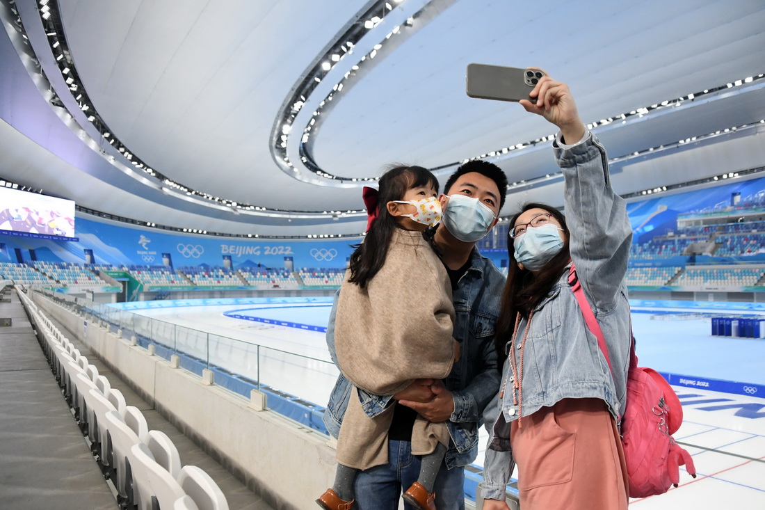 建设者张博伟（中）与家属在国家速滑馆“冰丝带”内合影留念（4月10日摄）。