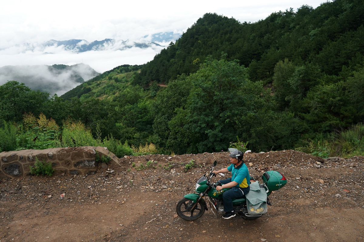 在山西省壶关县大峡谷镇，赵月芳骑行在送件的路上（7月13日摄）。新华社记者 詹彦 摄
