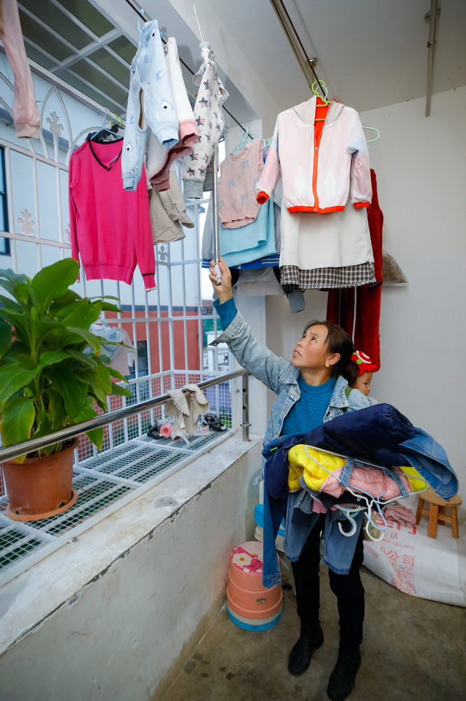 10月28日，在四川省凉山州越西县越城镇城北感恩社区，易地扶贫搬迁到此的沙马石各在阳台上收洗好的衣服，搬进楼房后她也用上了洗衣机。新华社记者 沈伯韩 摄